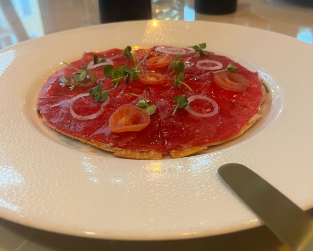 A plate of tuna crudo in the shape of a pizza