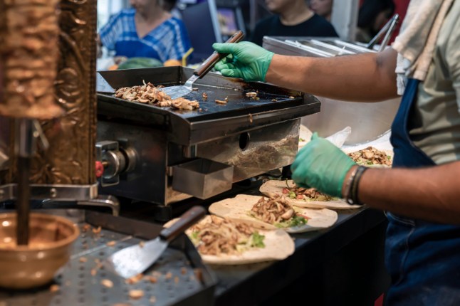 Preparation of Turkish shawarma. the cook's hands in rubber gloves apply a delicious chopped fried chicken meat with a spatula to put it into cakes with shawarma. street food, fast real life, ; Shutterstock ID 2041237460; purchase_order: -; job: -; client: -; other: